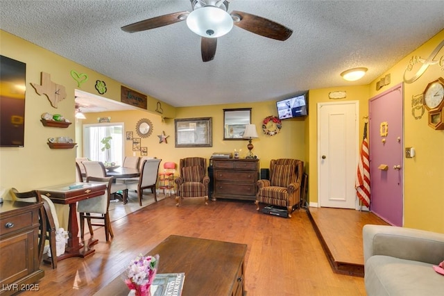 living room with ceiling fan, a textured ceiling, and wood finished floors