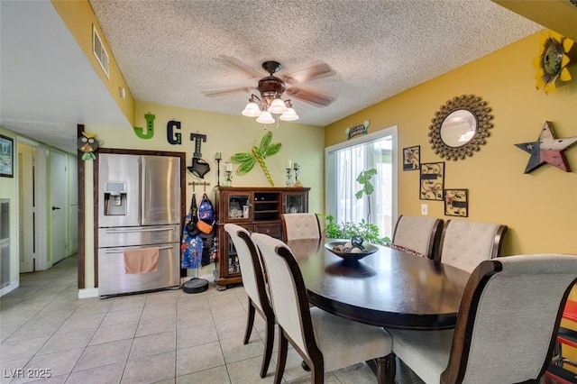dining area featuring visible vents, a textured ceiling, ceiling fan, and light tile patterned floors