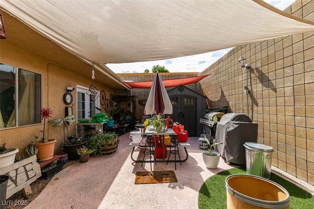 view of patio / terrace featuring a storage shed, an outbuilding, and a grill