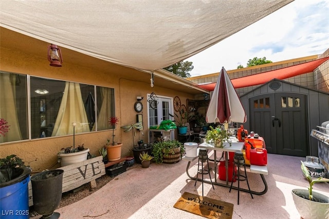 view of patio featuring an outdoor structure, outdoor dining space, and a storage unit
