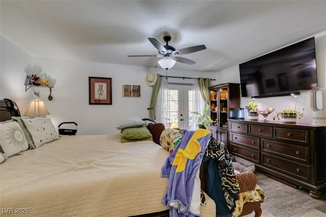 bedroom with a ceiling fan, french doors, wood finished floors, and access to exterior