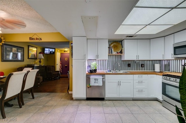 kitchen featuring a sink, light tile patterned floors, white cabinets, and stainless steel appliances