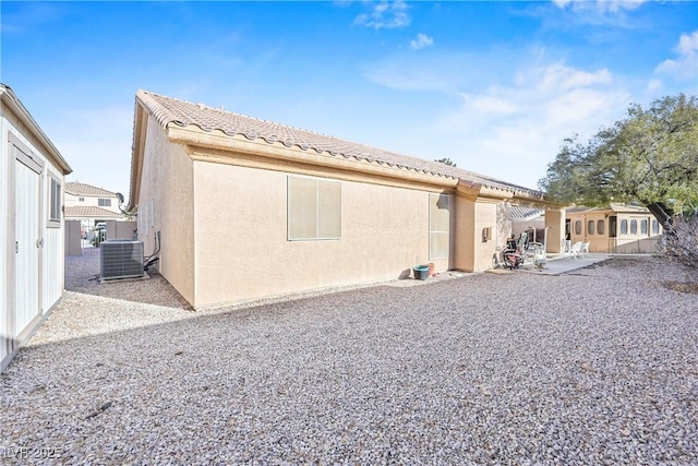 back of house with a tiled roof, a patio, central AC, and stucco siding