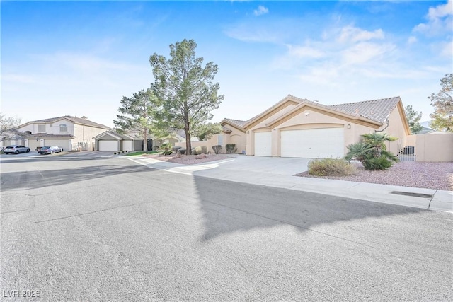 view of front of property featuring a tiled roof, a residential view, fence, an attached garage, and stucco siding