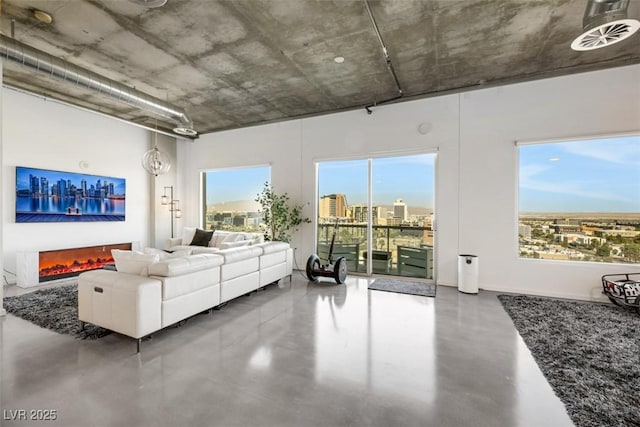 living area featuring a view of city, a lit fireplace, and concrete flooring