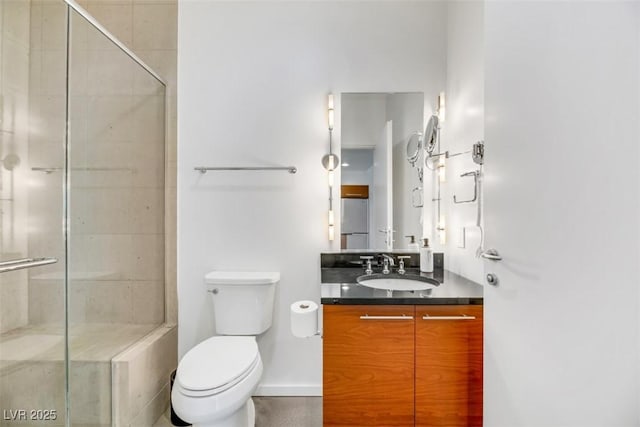 full bath with vanity, baseboards, a shower stall, and toilet