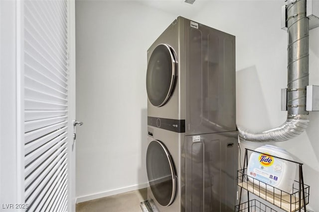 washroom with baseboards, laundry area, and stacked washer and dryer