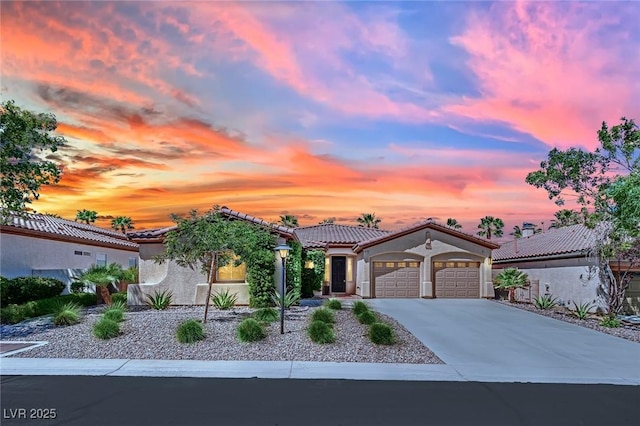mediterranean / spanish-style home with a garage, stucco siding, driveway, and a tile roof