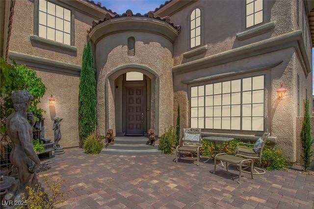 entrance to property featuring a patio and stucco siding