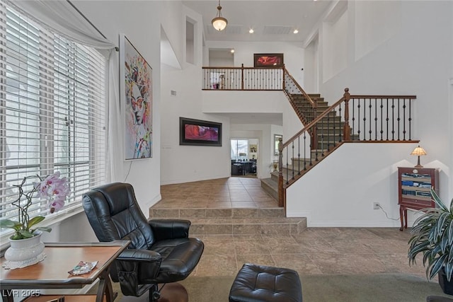 living room featuring tile patterned floors, stairs, recessed lighting, baseboards, and a towering ceiling