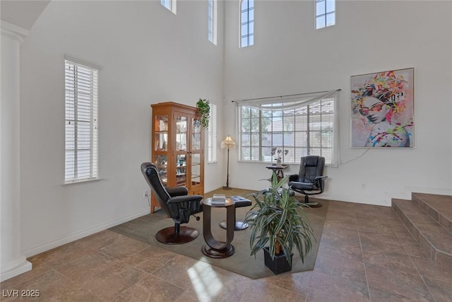sitting room featuring ornate columns, a high ceiling, and a wealth of natural light