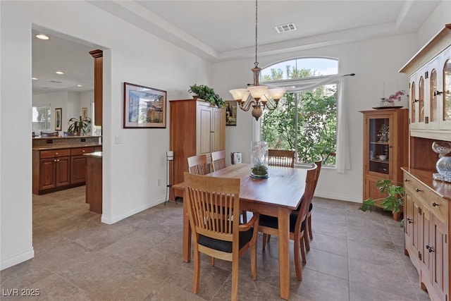dining space featuring an inviting chandelier, visible vents, baseboards, a tray ceiling, and light tile patterned floors