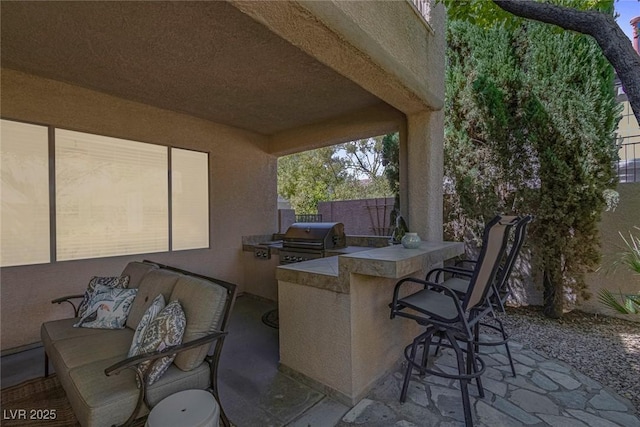 view of patio featuring fence, outdoor wet bar, grilling area, and an outdoor kitchen