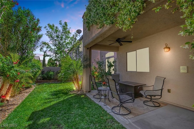 yard at dusk with ceiling fan, a patio area, and fence