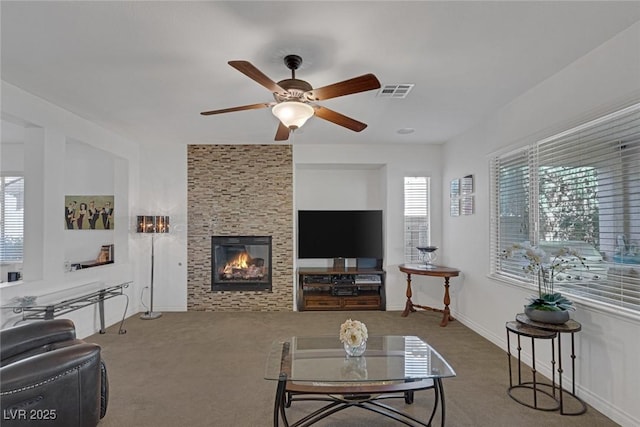 living area with visible vents, carpet, ceiling fan, and a large fireplace