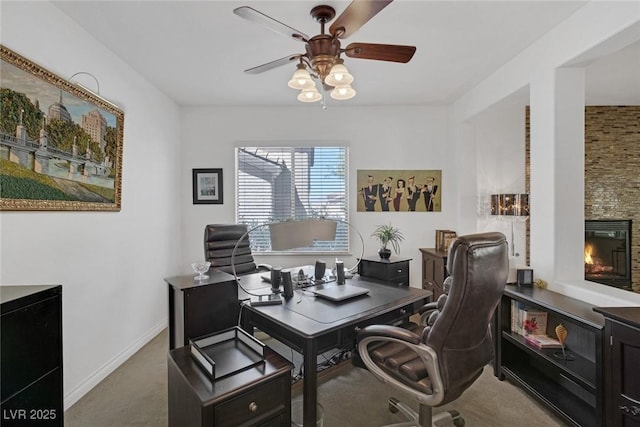 office featuring carpet floors, a ceiling fan, baseboards, and a fireplace