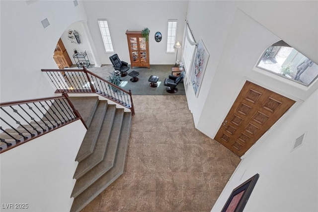 entrance foyer featuring visible vents, arched walkways, and a towering ceiling