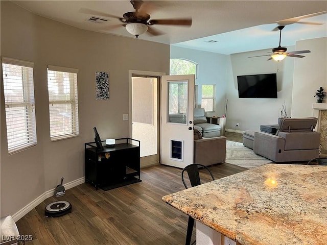 living area featuring a ceiling fan, baseboards, visible vents, and dark wood-style floors