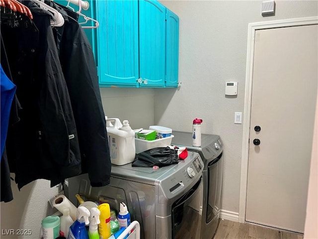 laundry area with wood finished floors, baseboards, cabinet space, and washing machine and dryer