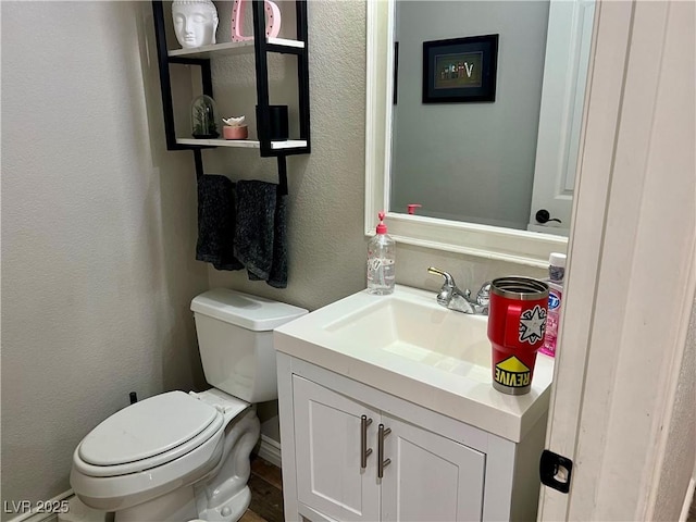 bathroom with vanity, a textured wall, and toilet
