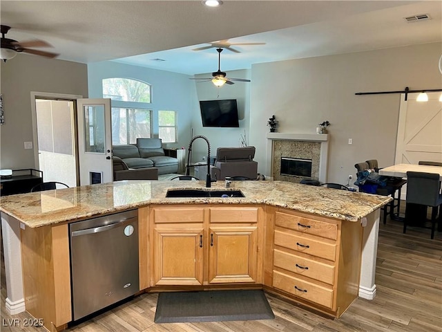 kitchen with stainless steel dishwasher, open floor plan, ceiling fan, and a sink