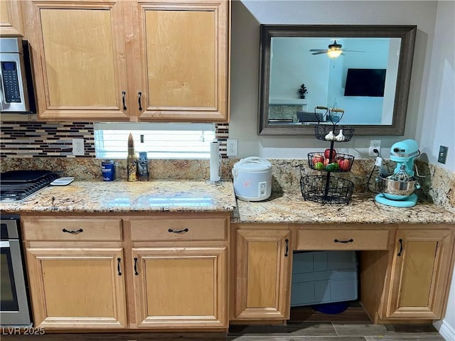 kitchen featuring ceiling fan, backsplash, light brown cabinetry, stainless steel microwave, and oven
