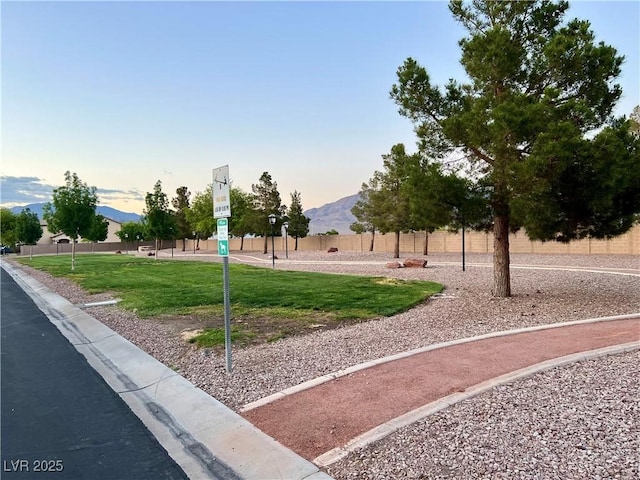 view of community featuring a lawn, fence, and a mountain view