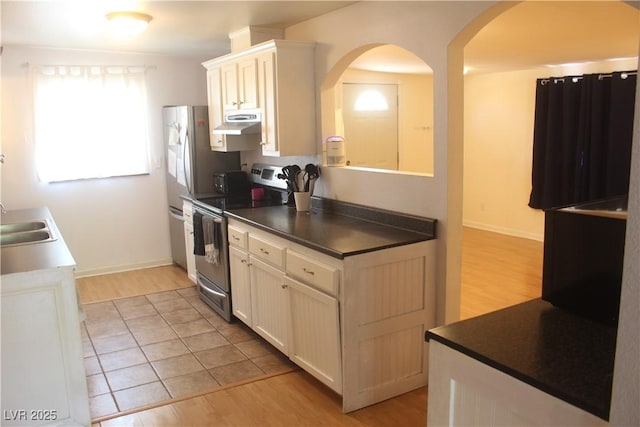 kitchen with appliances with stainless steel finishes, light wood-type flooring, and arched walkways