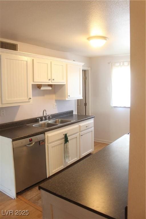 kitchen featuring visible vents, a sink, dishwasher, and dark countertops