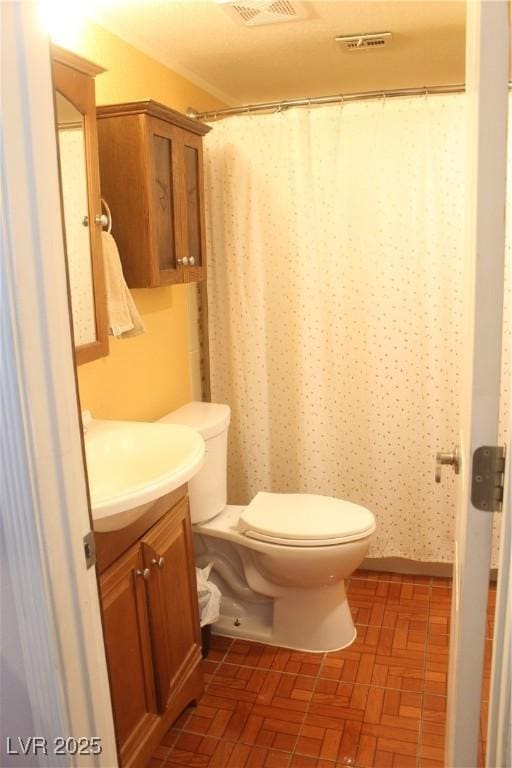 full bath with vanity, brick floor, and toilet