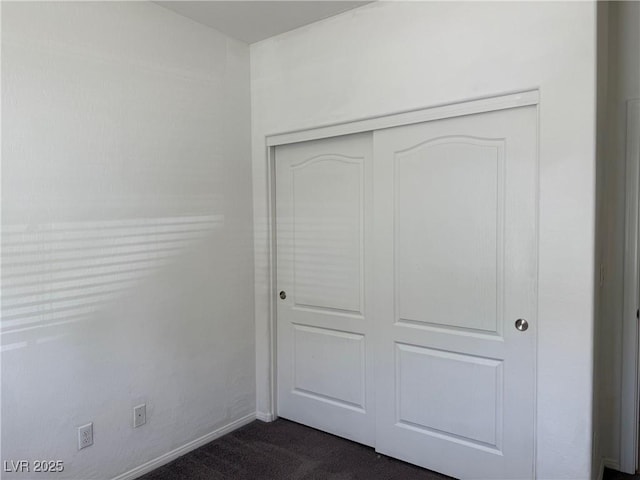unfurnished bedroom with baseboards, a closet, and dark colored carpet