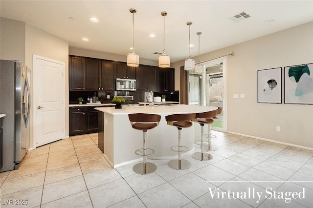 3163 Biccari Ave, Henderson, NV 89044 - kitchen featuring appliances with stainless steel finishes, light tile patterned flooring, light countertops, a breakfast bar area, and dark brown cabinets