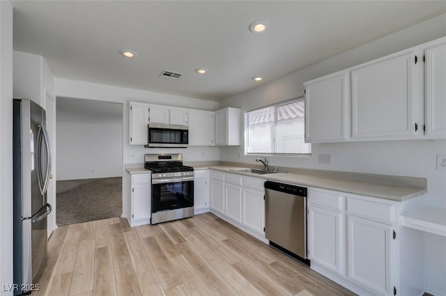 8877 Perfect Diamond Ct, Las Vegas, NV 89129 - kitchen featuring appliances with stainless steel finishes, a sink, light wood finished floors, white cabinetry, and visible vents
