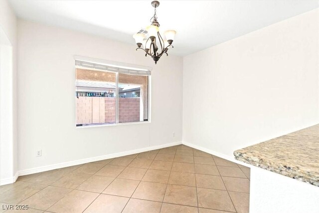 unfurnished dining area with an inviting chandelier, baseboards, and light tile patterned floors