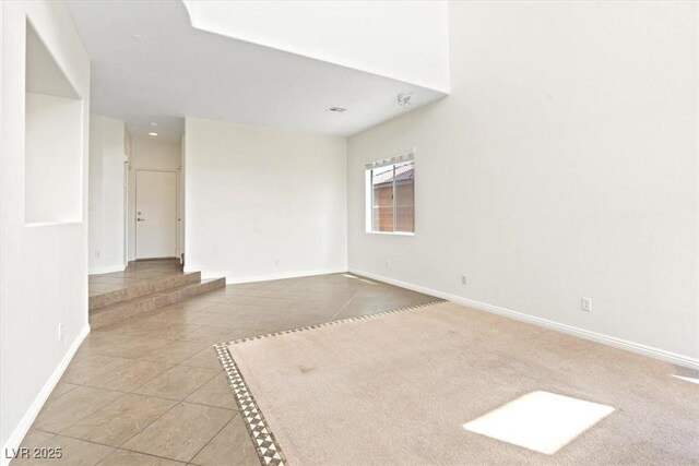 unfurnished room with baseboards and tile patterned flooring