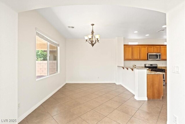 kitchen with visible vents, brown cabinetry, an inviting chandelier, light tile patterned flooring, and stainless steel appliances