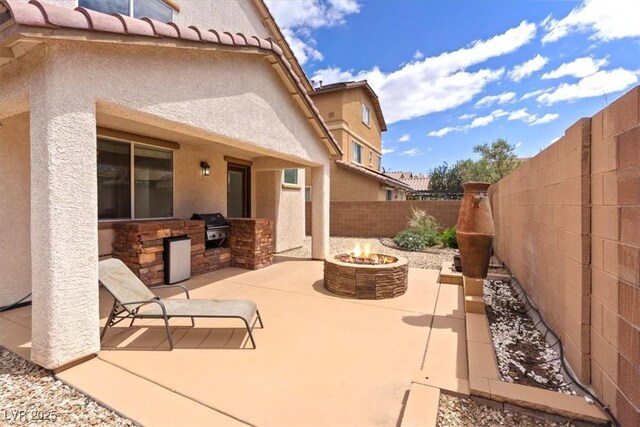 view of patio / terrace featuring a fenced backyard, a fire pit, grilling area, and an outdoor kitchen