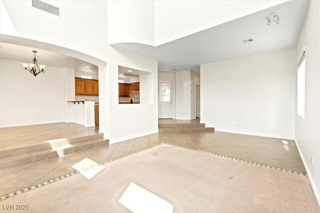 unfurnished living room with a notable chandelier, visible vents, and light tile patterned floors