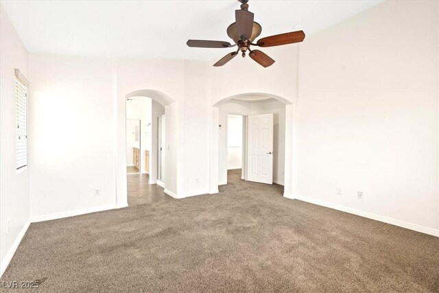 interior space featuring arched walkways, ceiling fan, and baseboards