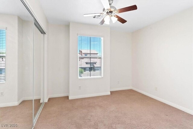 unfurnished bedroom with baseboards, ceiling fan, light carpet, and a closet