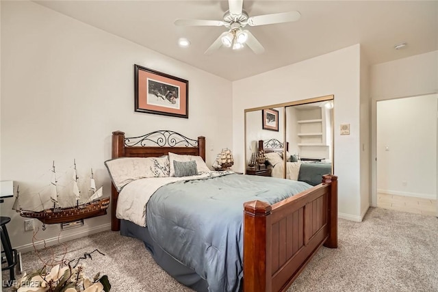 bedroom with baseboards, ceiling fan, light carpet, and a closet