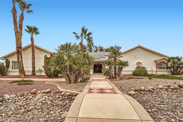 view of front of property with solar panels, a tile roof, and stucco siding