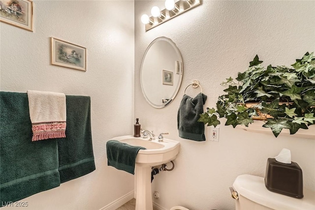 half bath with baseboards and toilet