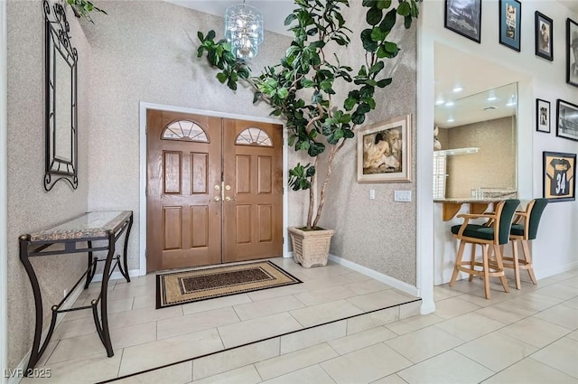 foyer featuring baseboards and a chandelier