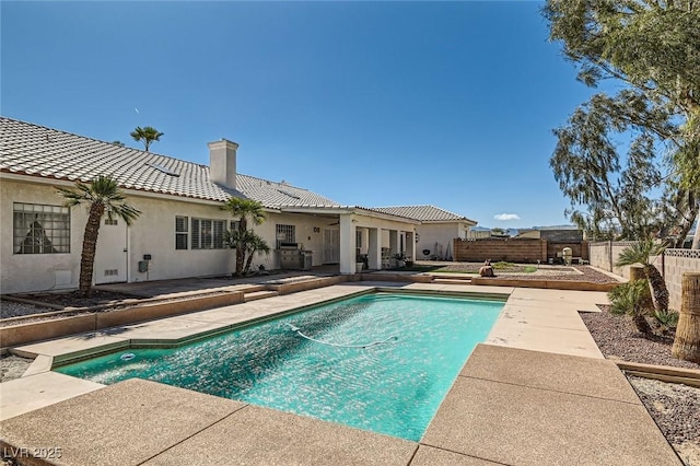 rear view of property with fence, stucco siding, a chimney, a fenced in pool, and a patio area