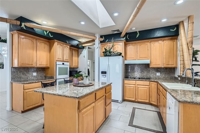 kitchen with a sink, light tile patterned floors, a skylight, and white appliances