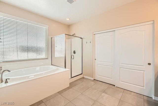 bathroom with tile patterned flooring, a bath, and a shower stall