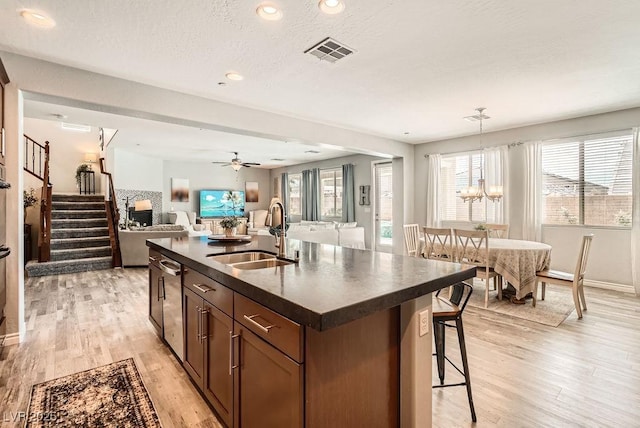 kitchen with visible vents, dark countertops, open floor plan, light wood-type flooring, and a sink
