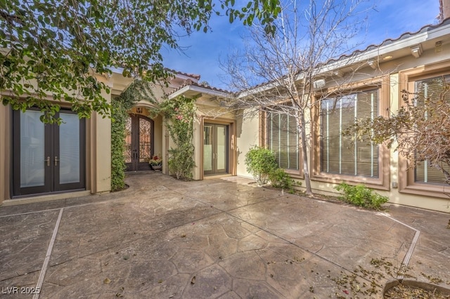 back of property with french doors, a patio, a tiled roof, and stucco siding