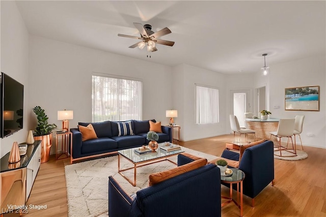 living area featuring baseboards, a ceiling fan, and light wood-style flooring